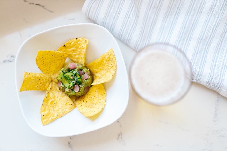 Fresh guacamole served with tortilla chips and a refreshing beverage, perfect for snacking.