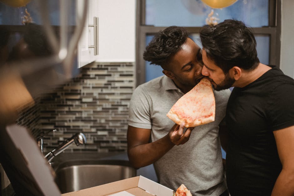 A loving gay couple sharing pizza in a cozy kitchen, celebrating togetherness.