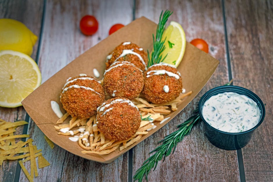 Delicious seafood balls served with rosemary, lemon wedge, and creamy herb sauce.
