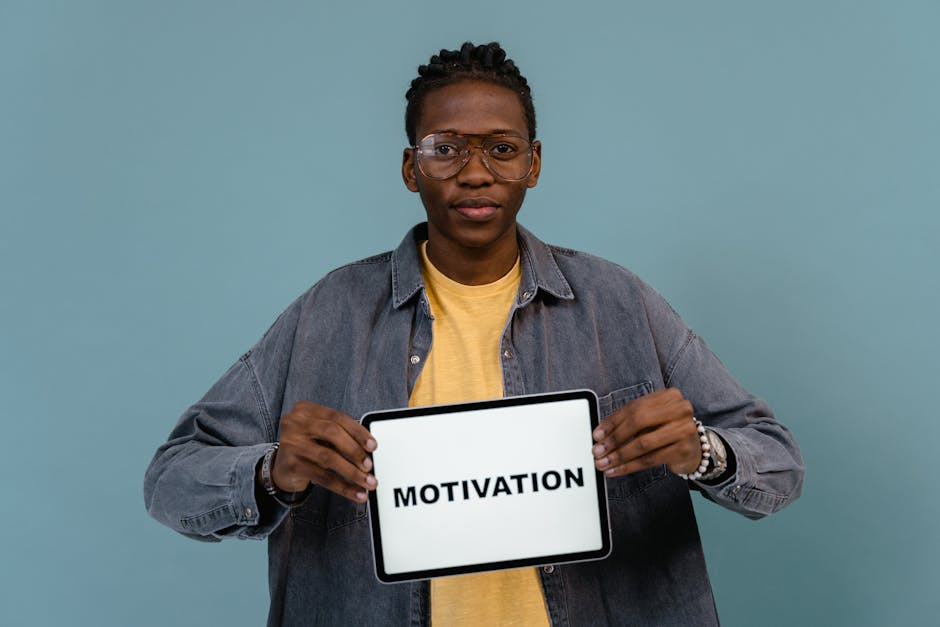 A young African American man holding a tablet displaying the word 'MOTIVATION' against a blue background.