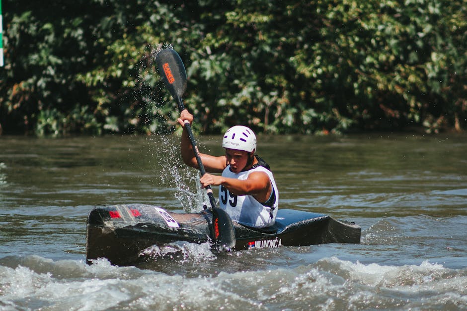 Man paddling a canoe with a helmet during a river competition.