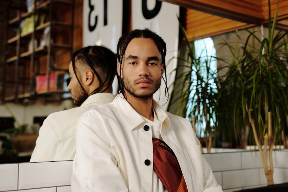 Portrait of a fashionable young man with afro braids and beard in a chic indoor space.