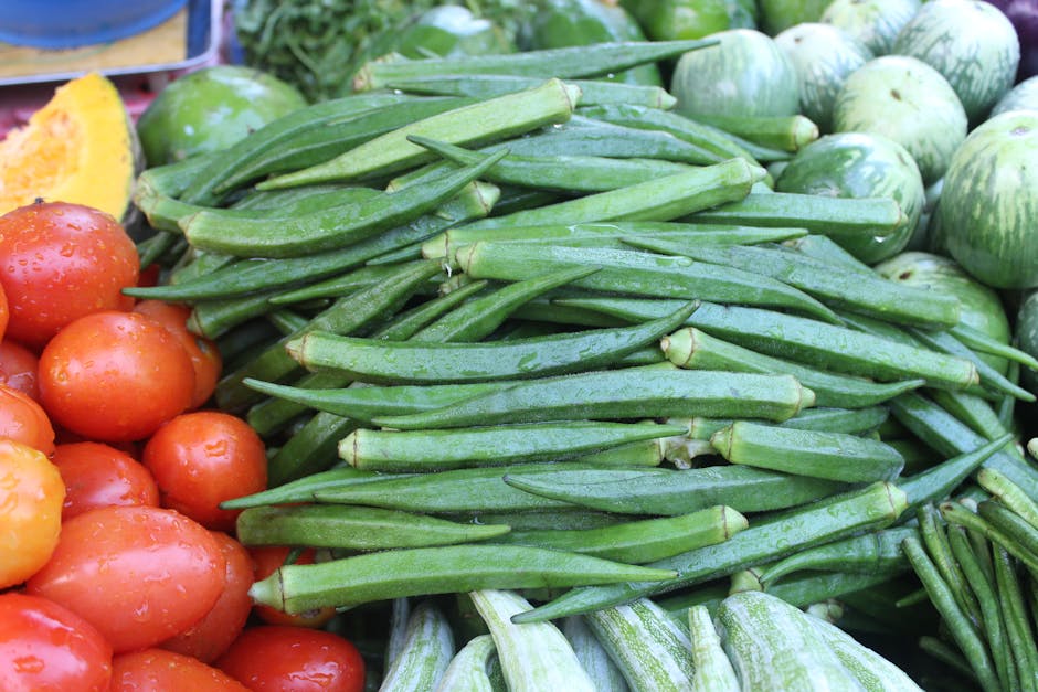Colorful fresh vegetables including okra, tomatoes, and squash at a market stall.