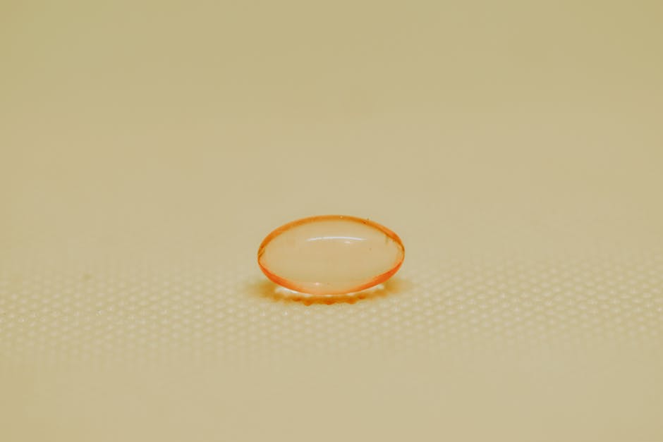 Detailed close-up image of a single orange medicine capsule on a textured surface.