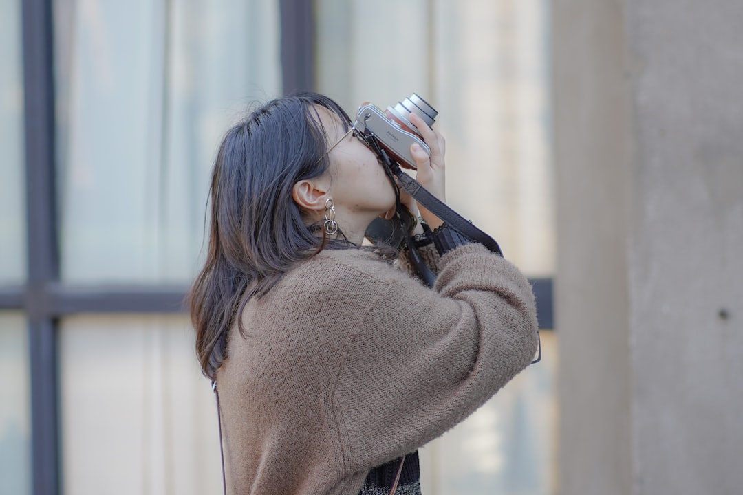 woman in brown sweater holding black smartphone
