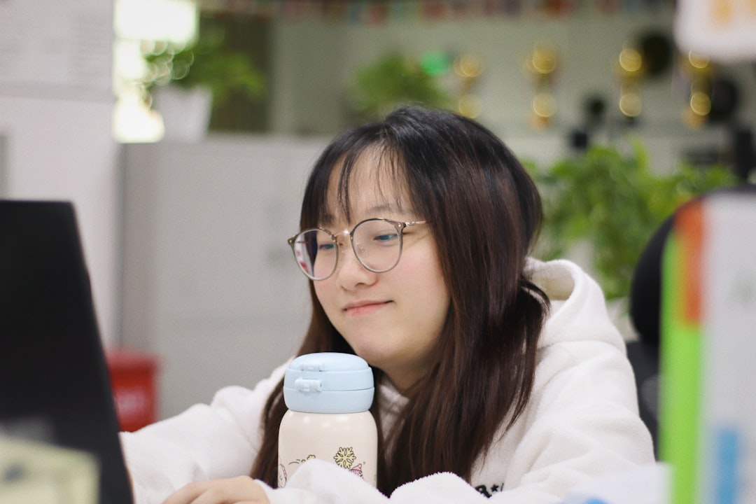 A young woman smiles while looking at a laptop.
