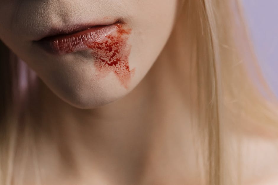 Detailed close-up of lips with a blood stain on the skin, highlighting texture and drama.