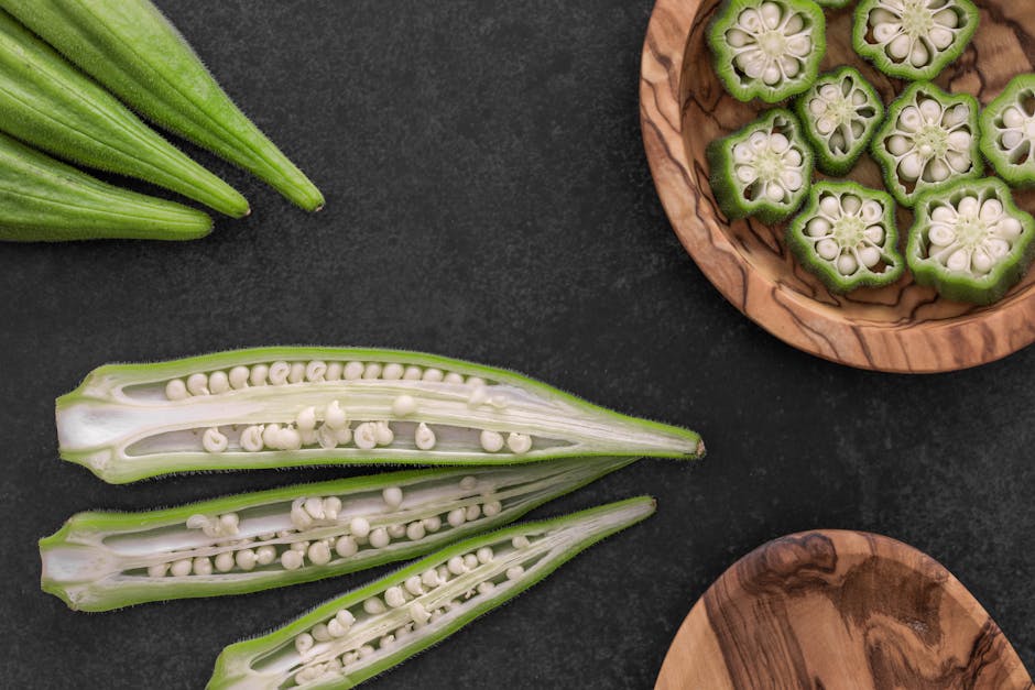 Close-up of fresh okra pods and slices on a dark background.