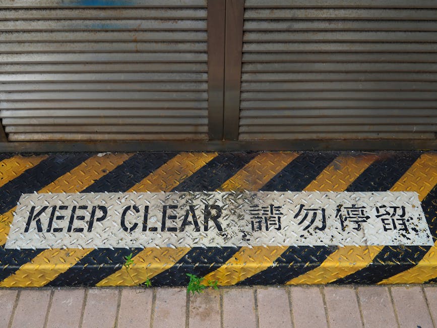 A bilingual 'Keep Clear' safety sign on a rusty metal floor in Hong Kong.