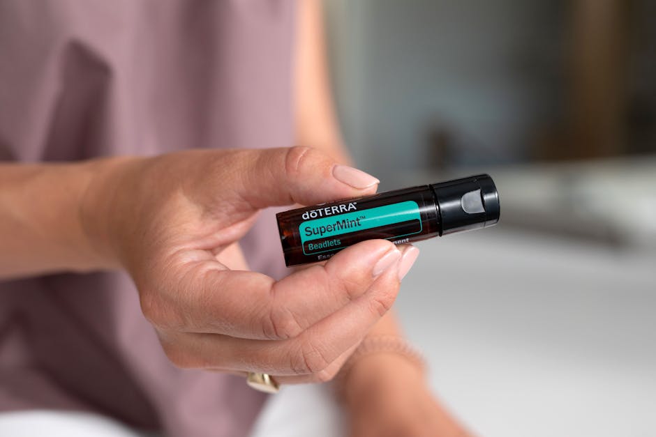 A close-up of a hand holding a doterra SuperMint supplement bottle, ideal for health concepts.