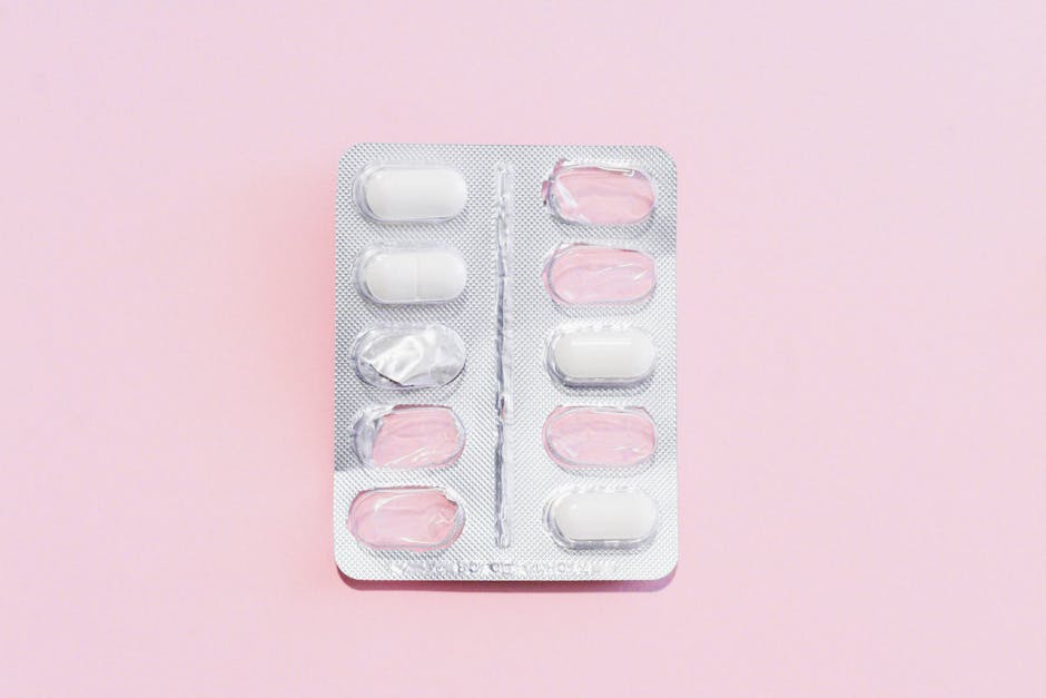 Close-up of blister pack with white pills on pink background, offering medical copy space.