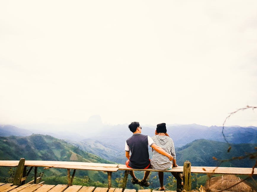 A couple sits on a bench, embracing while overlooking misty mountains in Laos.