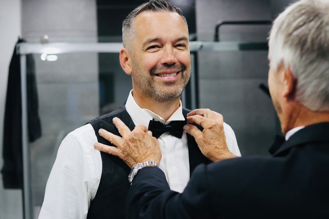 A man adjusting his bow tie in front of a mirror