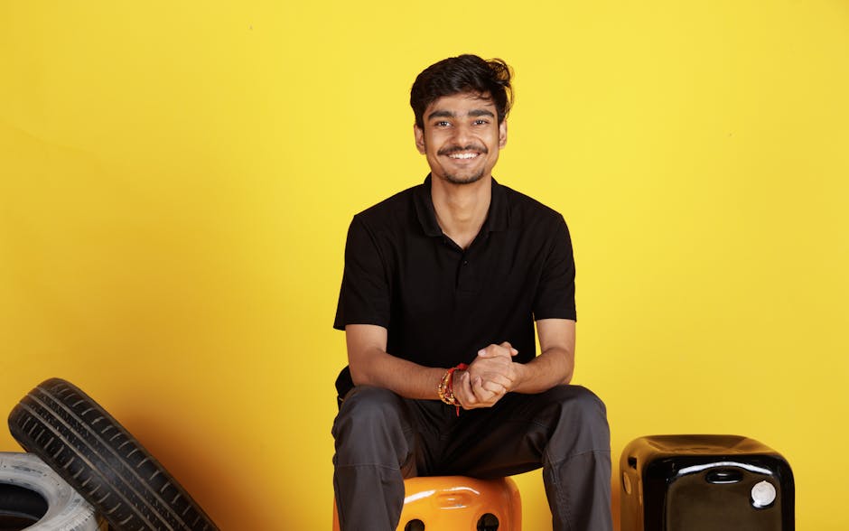 A cheerful young man in casual wear smiling against a vibrant yellow background. Indoors, positive vibe.