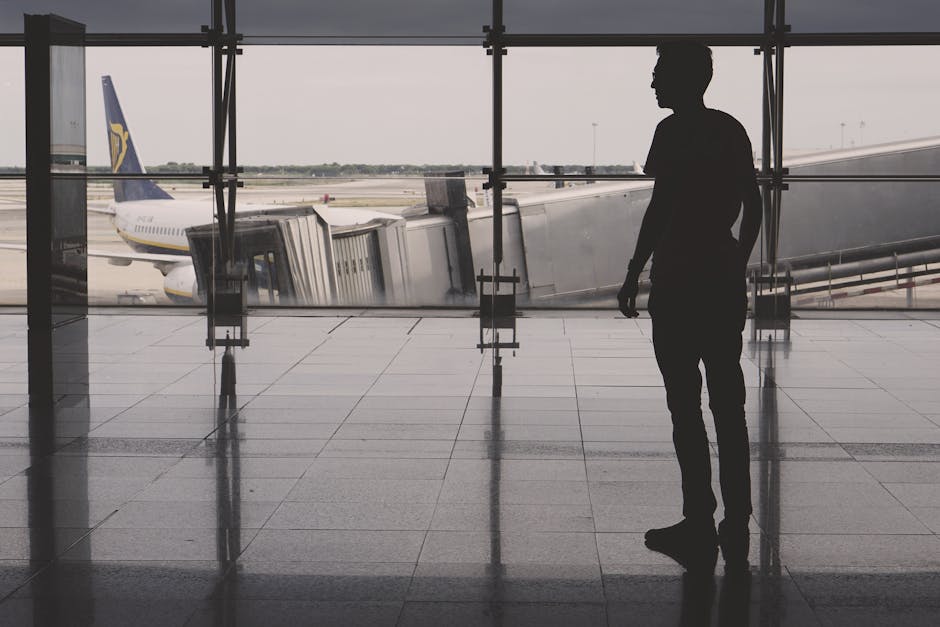 Silhouette of a man at El Prat airport with airplane reflections on glass walls.