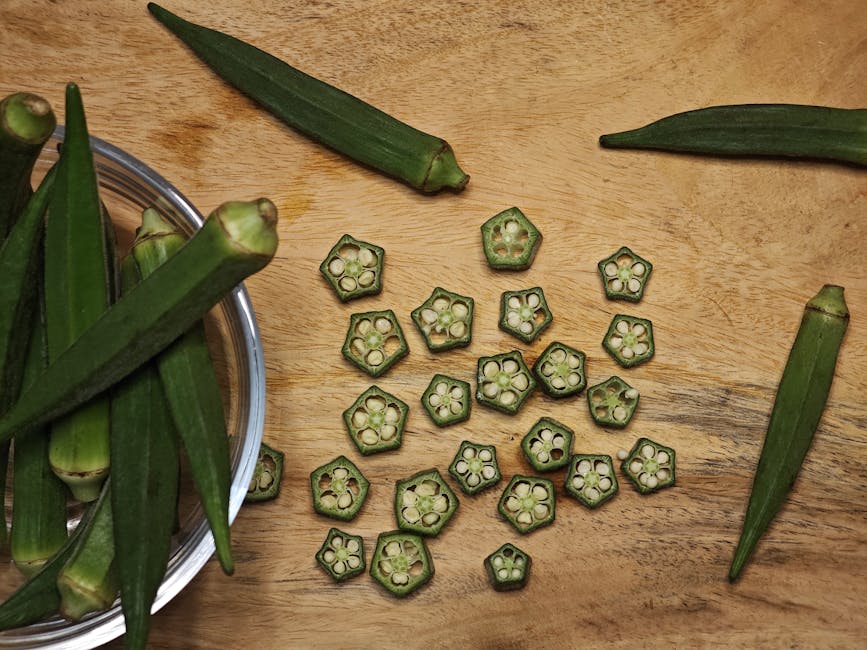 Top view of fresh and sliced okra (Abelmoschus esculentus) on a wooden surface, showcasing natural textures and colors.