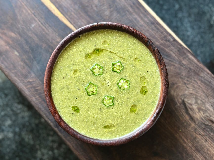 Top view of a vibrant green okra and broccoli soup in a wooden bowl, showcasing a healthy meal.