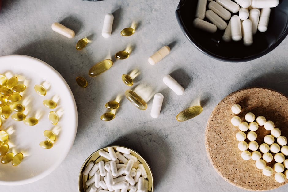 A variety of pills and capsules arranged on a grey surface, showcasing health and wellness.