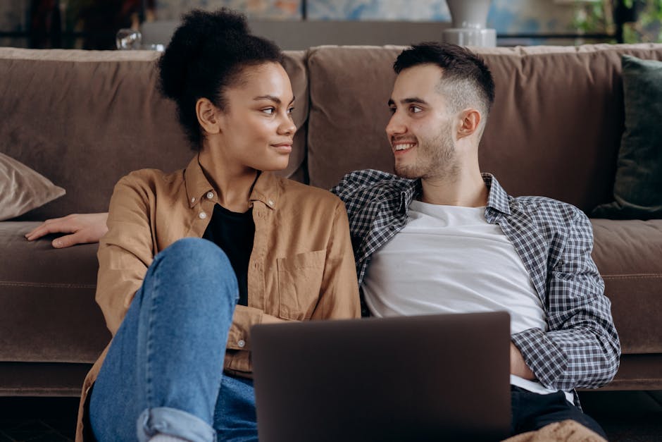 Happy couple sitting together on a couch with a laptop, enjoying each other's company.