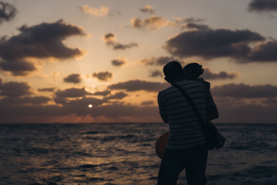 Silhouette of a father holding his daughter by the sea during sunset in Alexandria, Egypt.