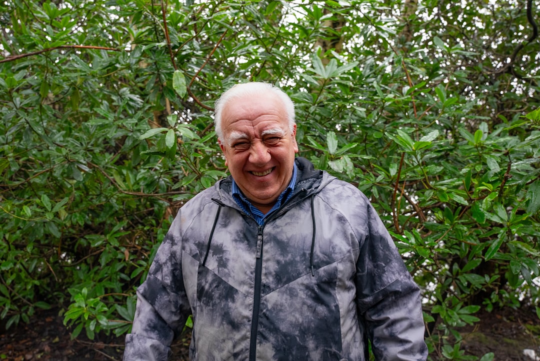 An older man standing in front of a bush